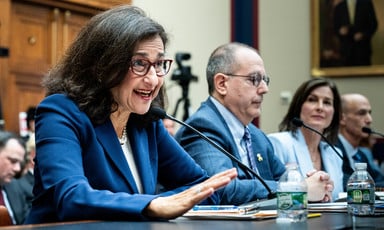 Minouche Shafik and two others sit at a table in a hearing room