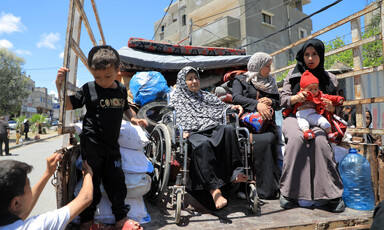 Women, one of them in a wheelchair, and children sitting in the back of a truck 