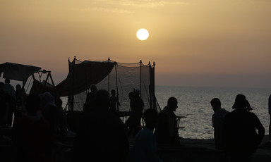 People beside the shore as it gets dark 