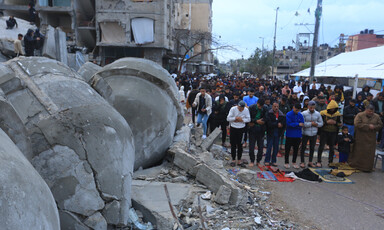 Men pray beside what remains of a mosque in southern Gaza 