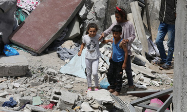 Three children amid what remains of a building destroyed by Israel 