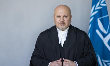 Portrait of Karim Khan in judicial robes next ICC flag