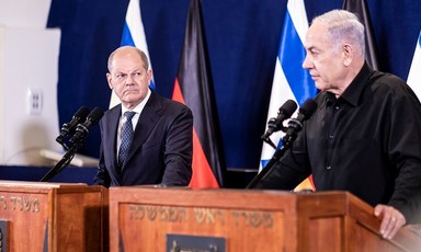 German Chancellor Olaf Scholz stands on a podium beside Israeli Prime Minister Benjamin Netanyahu
