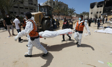 Men wearing masks and vests carry a body on a stretcher