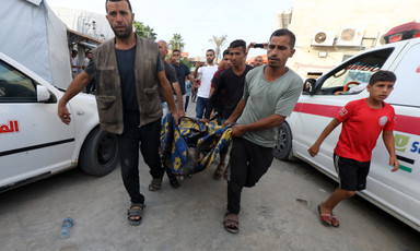 A number of men walk beside ambulances and carry a victim of an Israeli attack 