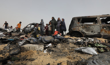 A number of people beside badly burned vehicles in southern Gaza 