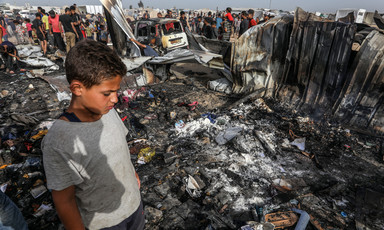 A boy looks down at charred personal belongings