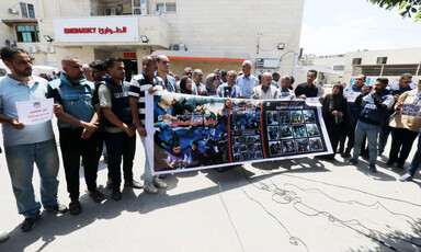 Journalists hold up a banner depicting their slain colleagues