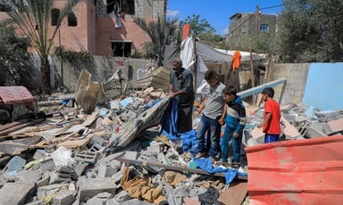 A man and three children stand on top of a pile of rubble