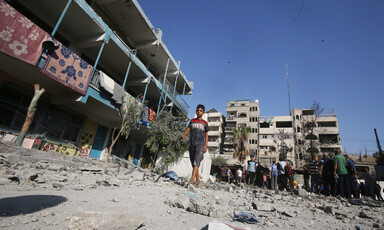A boy walks beside a school which has been attacked by Israel 
