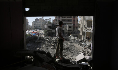 A man looks out from a damaged building at destruction around him in central Gaza 