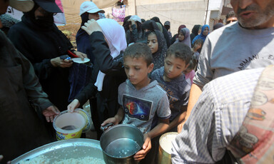 Children and some adults hold pots as they queue for rice in Gaza 