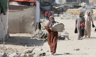 A number of people walk through an area that has been attacked by Israel in southern Gaza 