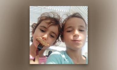 A close-up of two girls smiling and having a snack