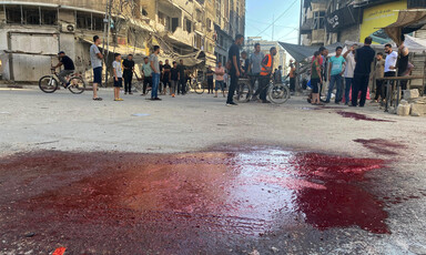 People stand near a large blood stain in Gaza City 