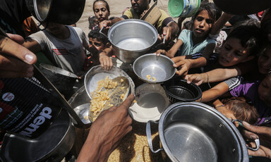 Children and at least one adult hold pots and other utensils as food aid is distributed in Gaza 
