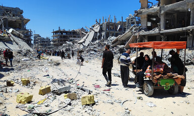 People go through a destroyed refugee camp on foot and in carts 