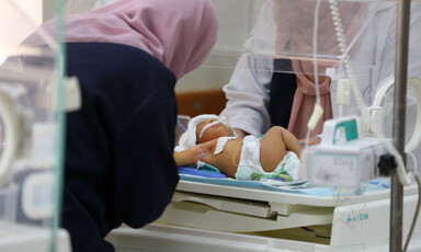 A woman leans over a baby