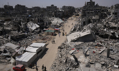 A bird's eye view of a dirt road with destroyed buildings and rubble on either side
