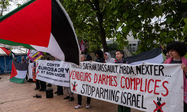 Protesters with a Palestinian flag and banners protesting against cooperation between France and Israel 