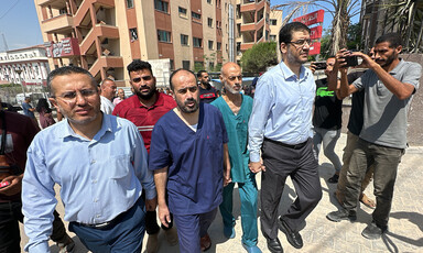 Men hold hands while walking in front of hospital