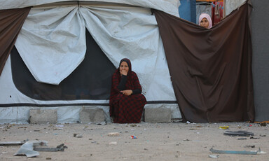 A woman sits in front of a makeshift tent