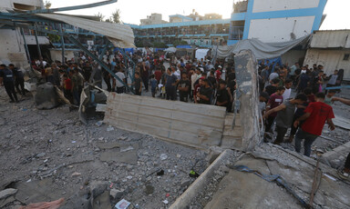 People gather in a hugely damaged school after it was attacked by Israel 