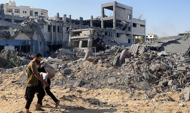 A man walks in the foreground of a destroyed building