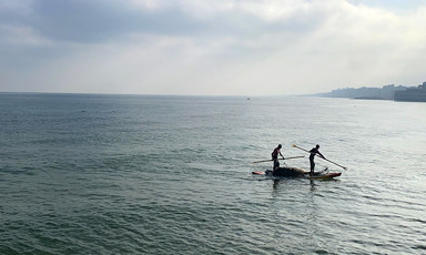 Two fishers at sea in a small boat 