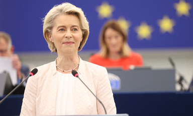 European Commission President Ursula von der Leyen stands at a podium with two microphones 
