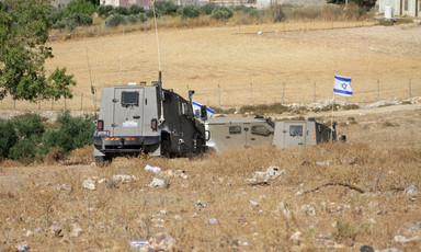 Israeli armored vehicles and Israeli flag in a field 