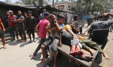 Four Palestinian men and boys, some of them streaked with blood, sit and lay on a donkey-drawn cart as bystanders look on