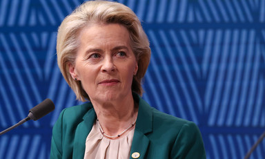 European Commission President Ursula von der Leyen seated in front of a blue backdrop 