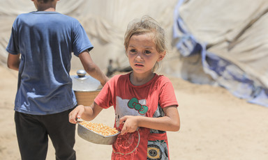 A child carries a bowl of food