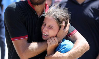 A girl crying is held tight by a man