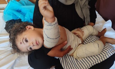 An injured child held by a woman sitting on a hospital bed