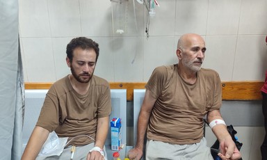 Two men sit on chairs in a hospital or a clinic 