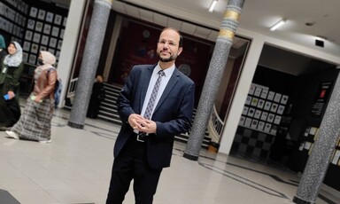 Dr. Refaat stands in an atrium wearing a suit