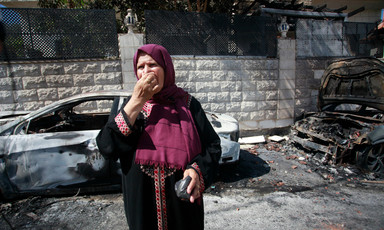 A woman stands in the street near burned vehicles 