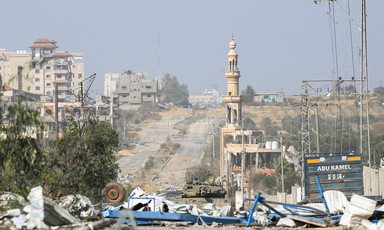 A daytime view of a street with ruins of buildings and an Israeli tank. 