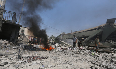 In the center of a scene of gray rubble is a red fire emitting black smoke