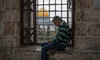 Aman sits by a window overlooking the Aqsa mosque