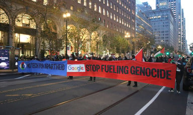 Demonstrators block a street with two large banners 