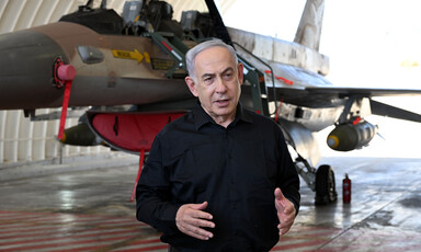 Israel's Prime Minister Benjamin Netanyahu stands in front of a warplane 