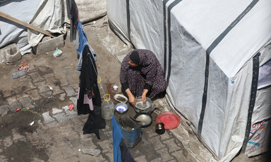 A view from above of a woman near a white tent, washing dishes.