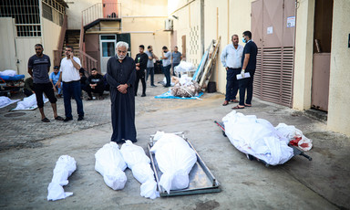 Men standing near shrouded bodies outside Al-Aqsa Martyrs Hospital in Deir al-Balah