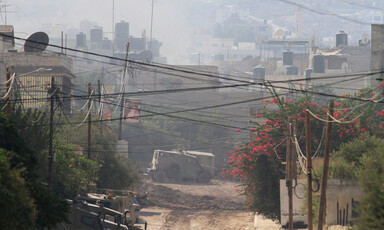 An armored vehicle is seen amid the dust on torn-up roads