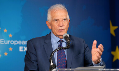 European Union Representative Josep Borrell stands in front of a microphone with a blue background behind him 