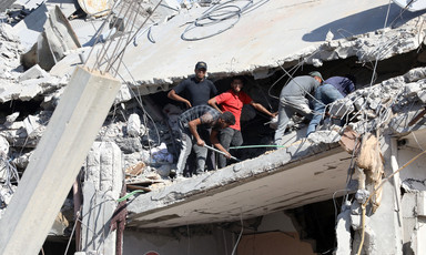 Men stand in the rubble of a building