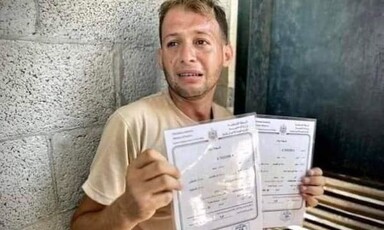  A tearful man holds up to certificates 